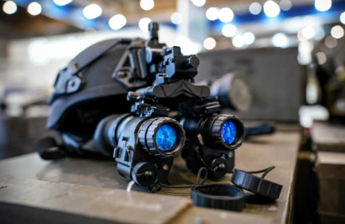 Military helmet with mounted PVS-31 night vision goggles featuring dual blue lenses.