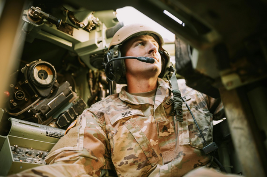 Soldier wearing tactical headset with ARC rail adapter inside military vehicle